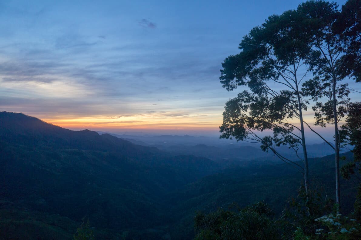 Watching the sunrise over the mountains on top of Ella rock in sri lanka