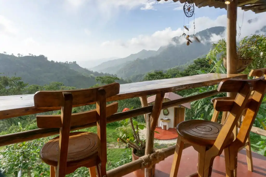 Two chairs overlook a breathtaking mountain scene at a hostel in Minca, Colombia, providing the perfect spot for reflection, connection, and appreciation of nature's awe-inspiring beauty.