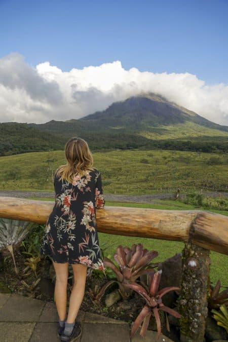 girl looking over arenal volcano in 1968 park while hiking in la fortuna 