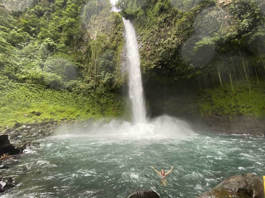 girl swimming under la fortuna waterfall
