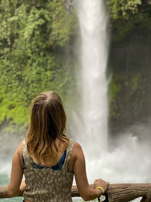 girl looking up at la fortuna waterfall
