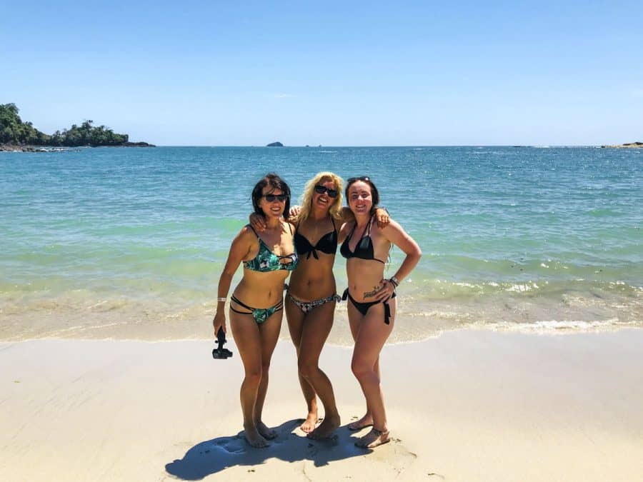three girls on sand by turquoise water in costa rica