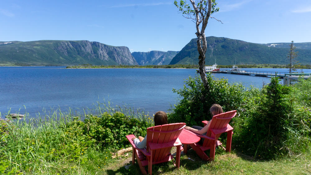two tourists in red chairs looking at ocean in gros morne national park