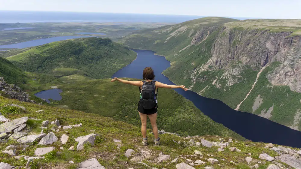 lora with arms wide open overlooking mountains in gros morne national park