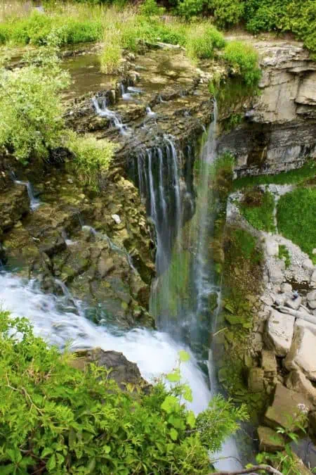 Spectacular waterfall cascading down rocky cliffs surrounded by lush greenery in Hamilton, Ontario