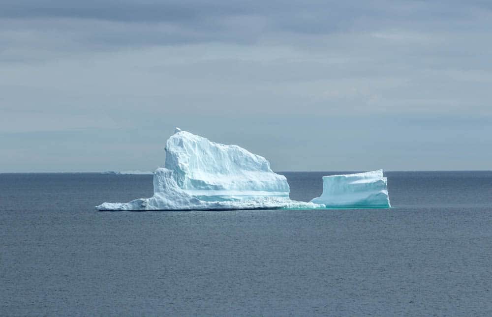 a large iceberg sits in the atlantic ocean in newfoundland