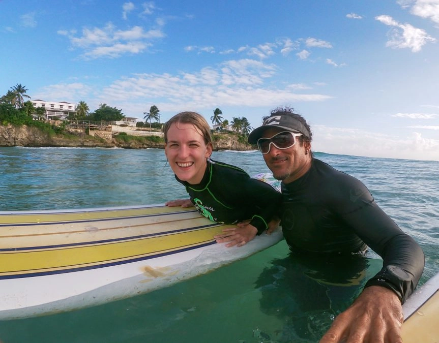 Lora on surfboard with instructor