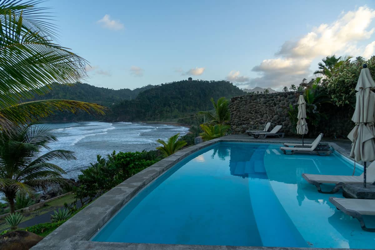 outdoor pool at a hotel in dominica overlooking the atlantic ocean. it is empty and the sun is setting.