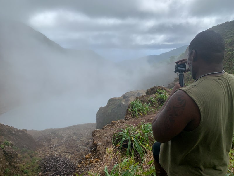 man taking a photo of boiling lake