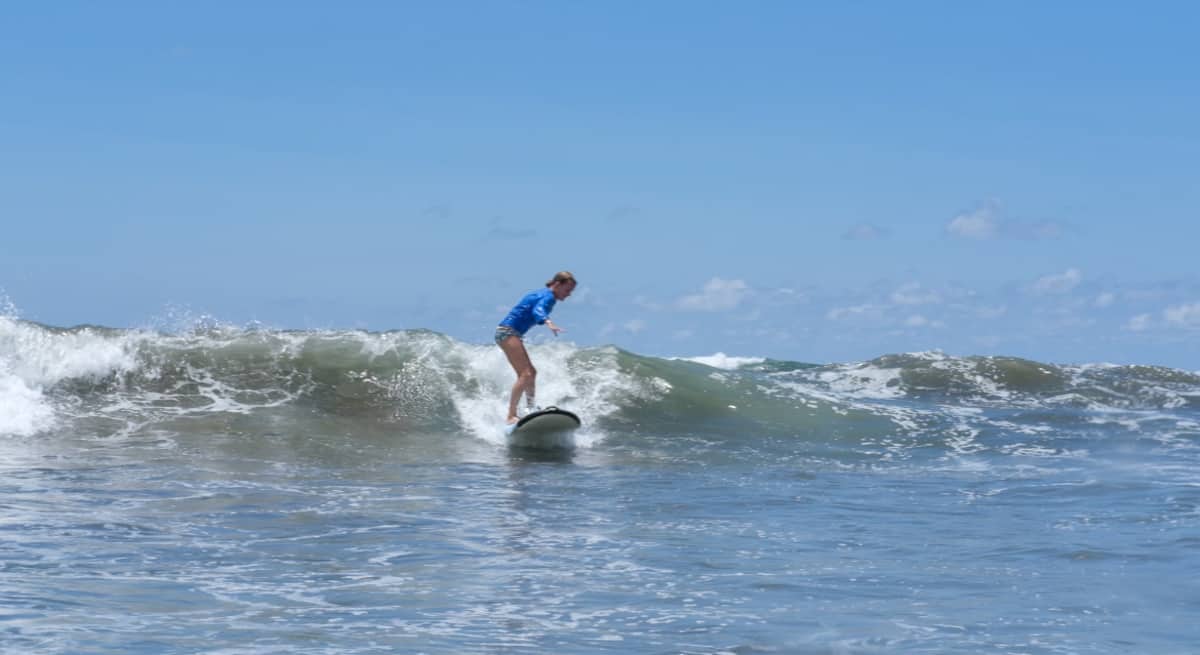 Lora catching a wave while surfing in the Pacific Ocean off the coast of Uvita Costa Rica