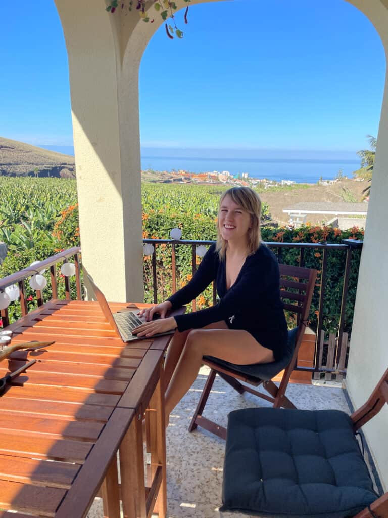 lora working on her laptop in tenerife spain. the ocean is in the background.