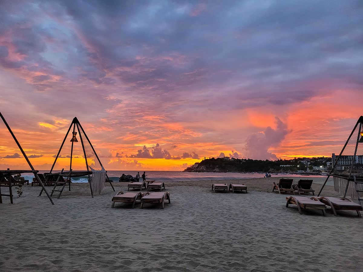 Breathtaking pink and orange sunset casting a warm glow over the serene beach in Puerto Escondido, Mexico.