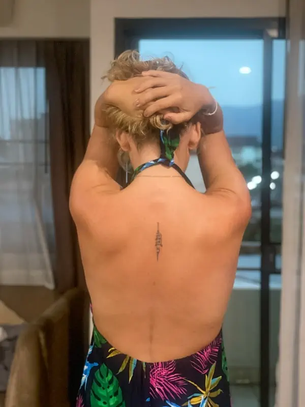 lora from back on with her sak yant tattoo in the middle of her back