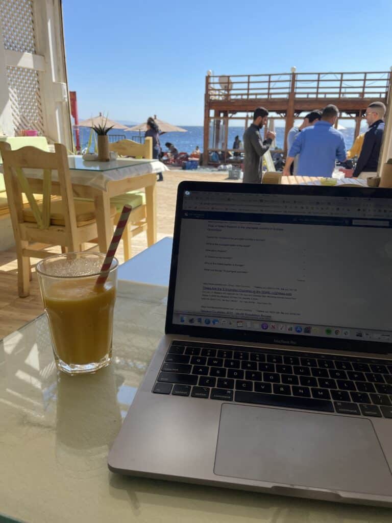 computer with smoothie in cafe by sea