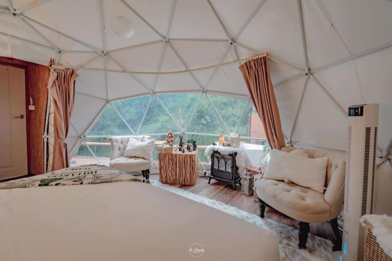 inside of glamping dome with bed and chairs