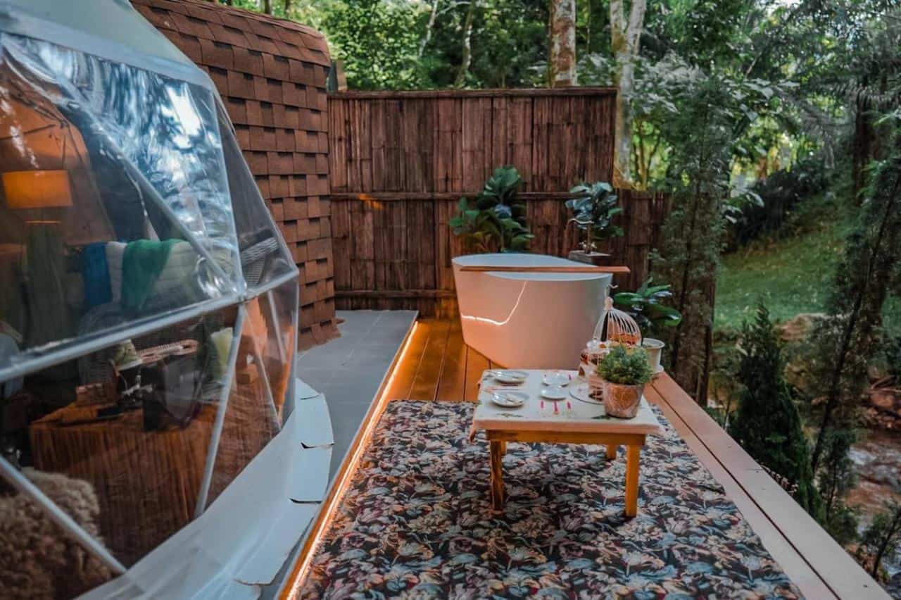 bathtub and tables with plates outside of glamping dome
