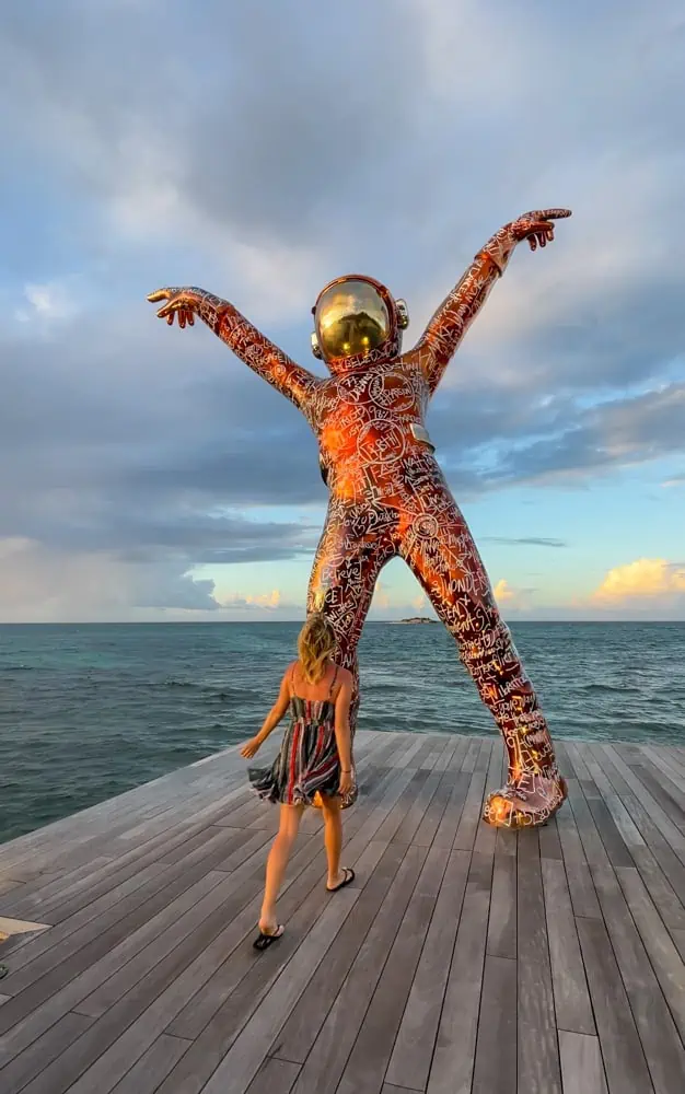 lora walking a spaceman status on a wooden dock with the ocean in background