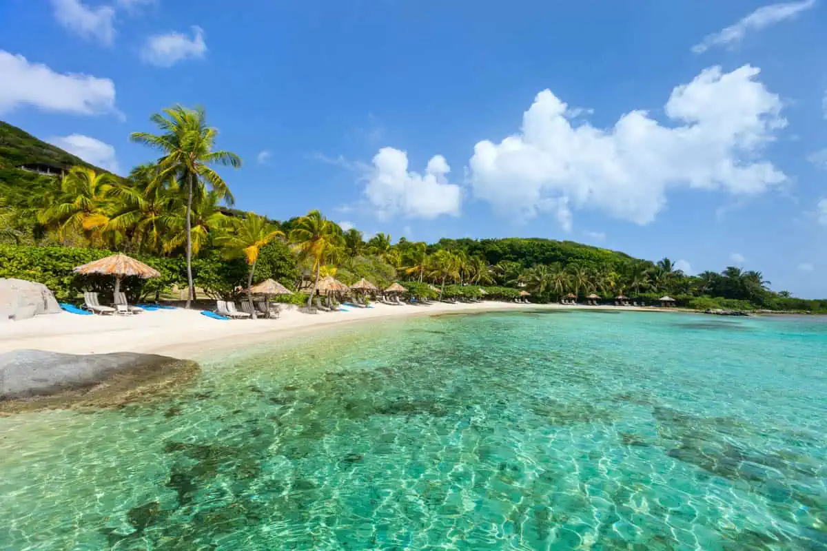 Beautiful tropical beach with palm trees, white sand, turquoise ocean water and blue sky at British Virgin Islands in Caribbean