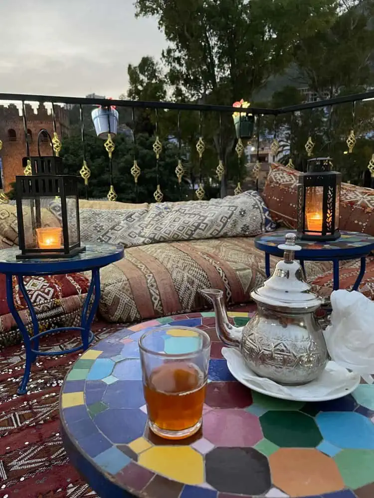 cup of tea on a colorful table surrounded by colorful ornaments and candles. peaceful setting in morroco.