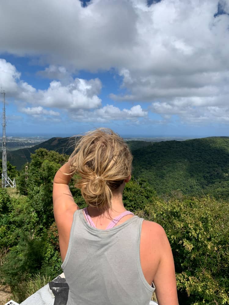 lora looking out at rolling green hills from mount obama in antigua