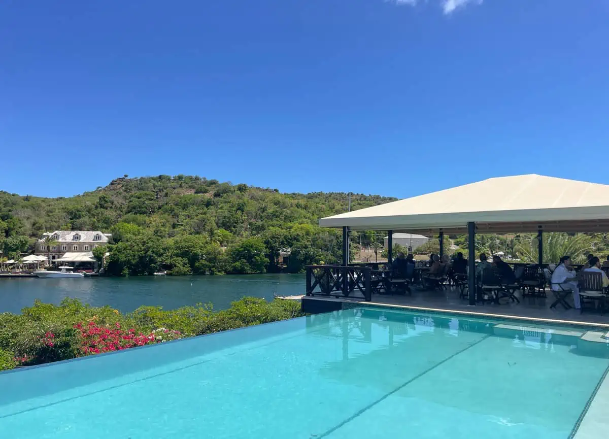 people sitting in a restaurant next to a pool that overlooks the ocean.