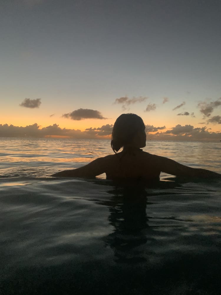 lora in the caribbean ocean looking at the sunset over the horizon of the ocean in antigua