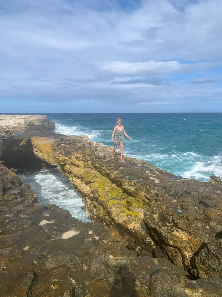 lora walking on a natural rock arch in Antigua