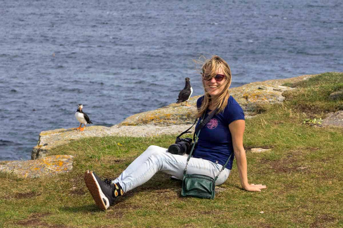 lora smiling happily with two puffins behind her