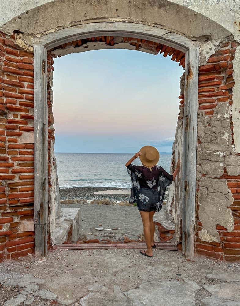 A woman standing in a doorway looking out to the ocean.