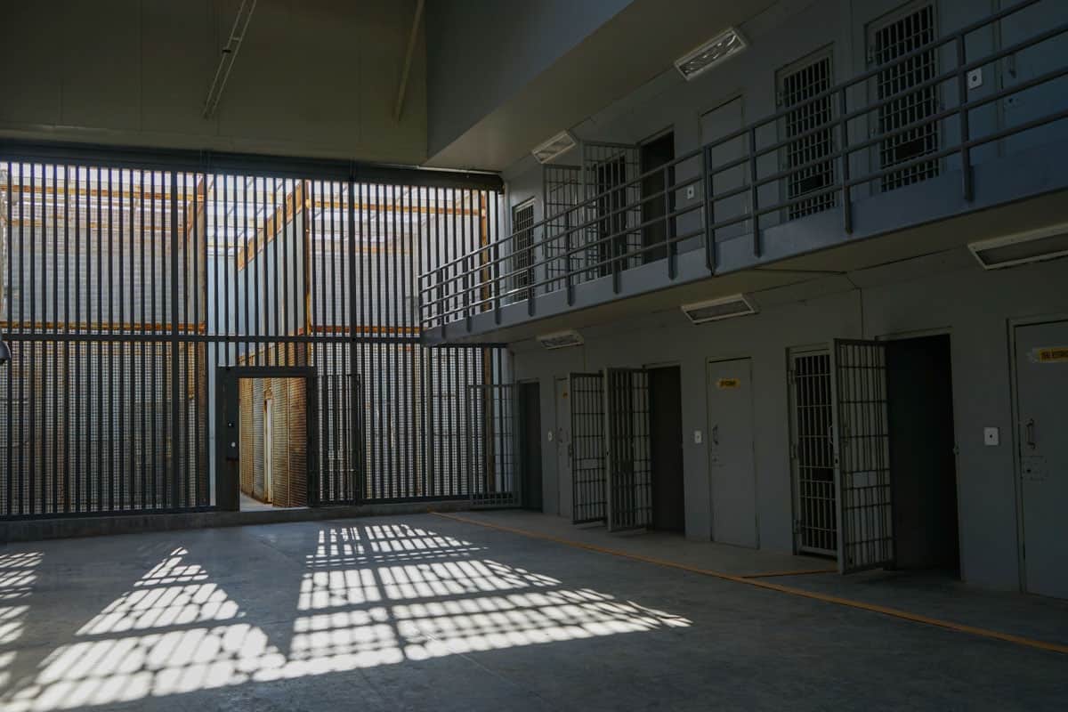 The inside of a prison cell with bars on the windows.