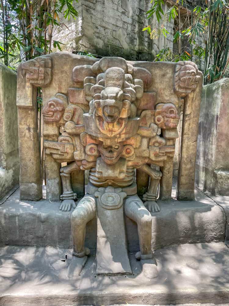 A statue of a deity sitting on a bench.