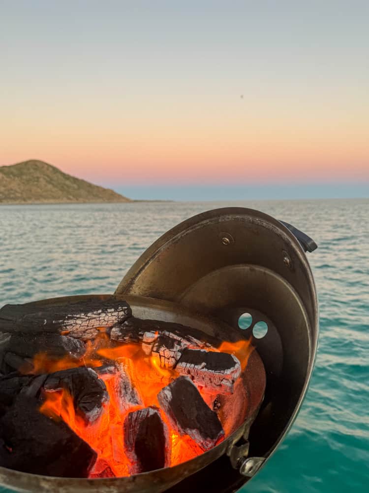 A barbecue grill on the ocean at sunset.