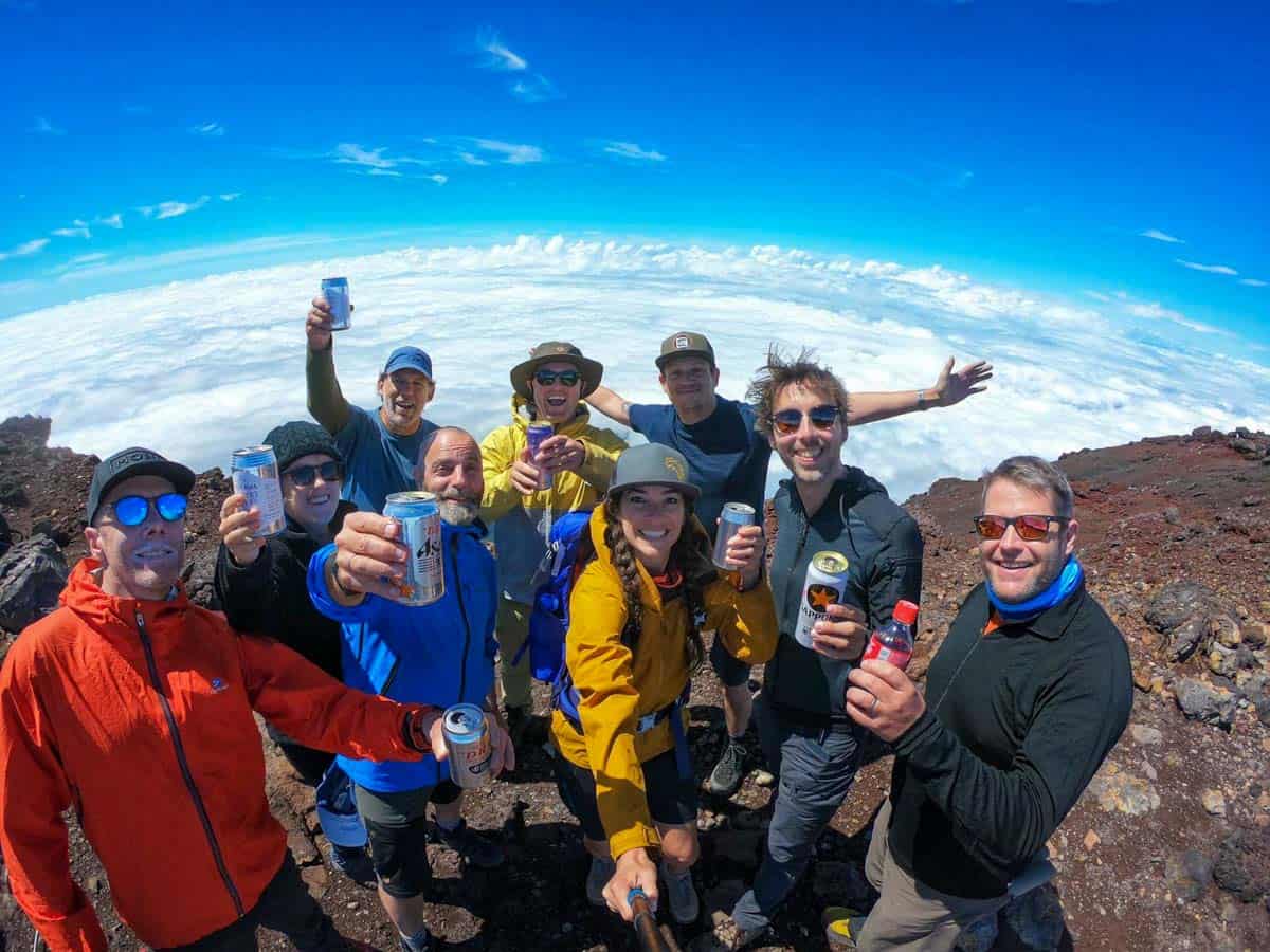 A group of people standing on top of a mountain with beer in their hands.