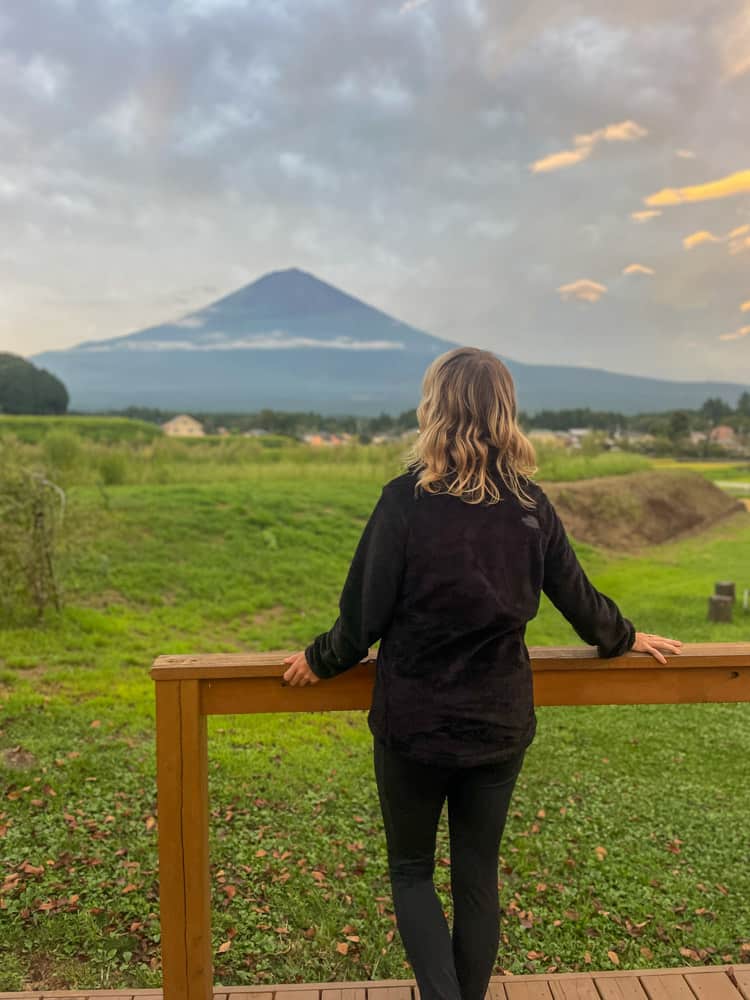 A woman looking out over a field with mt fuji in the background.
