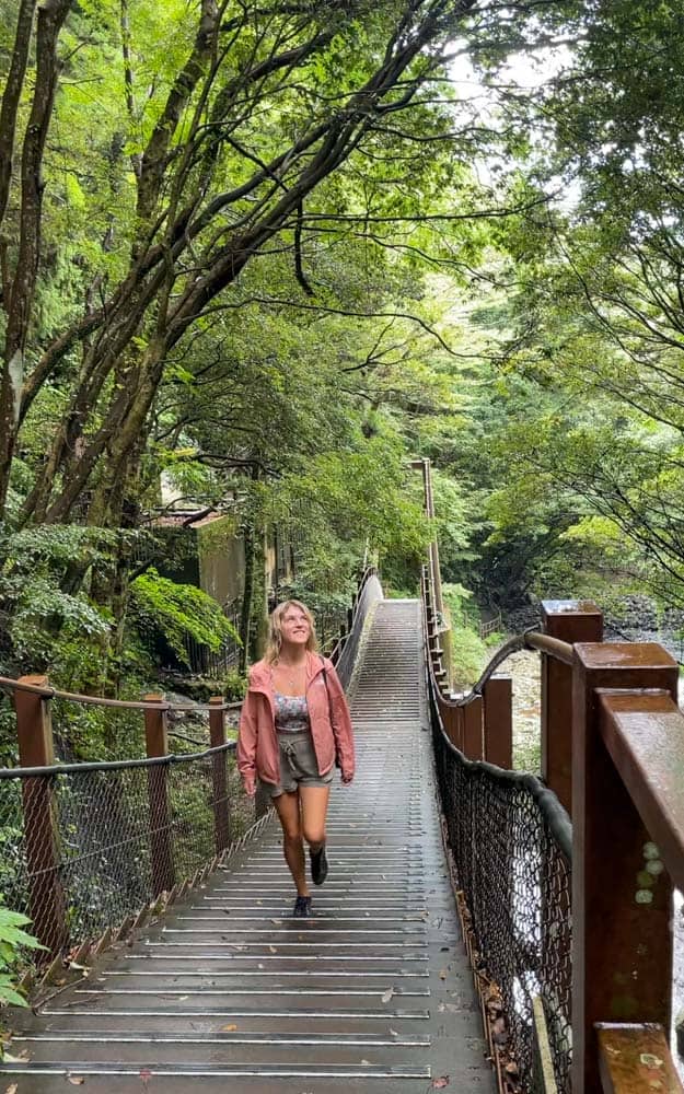 A woman walking on a wooden bridge in a forest.
