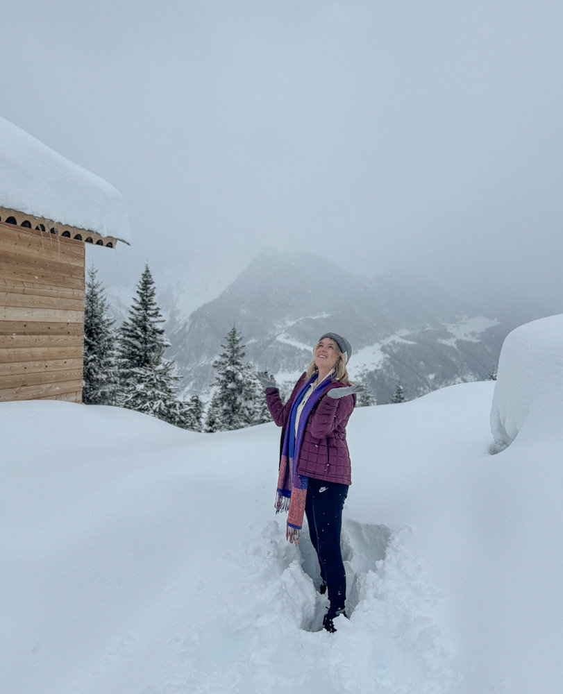 A woman standing in front of a snow covered cabin.