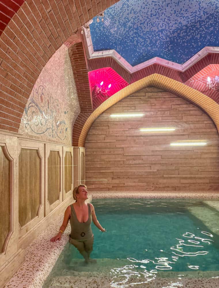 A woman is sitting in a pool inside a building.