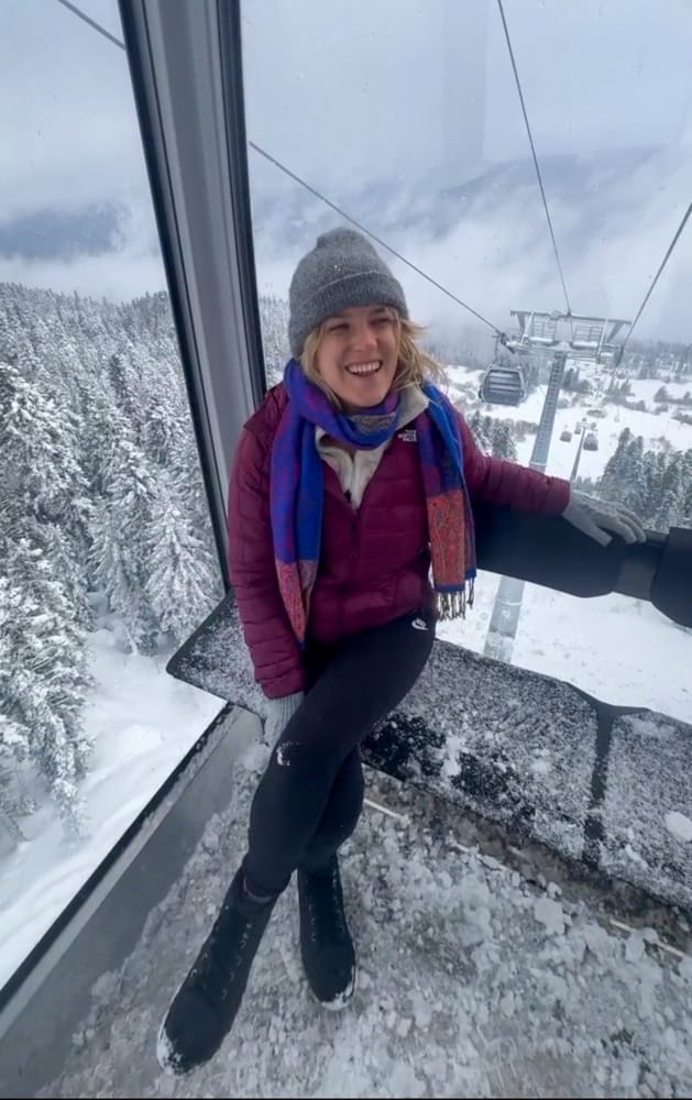 A woman sitting on a gondola in the snow.