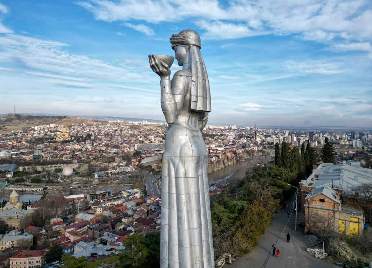A statue of a woman standing on top of a city.