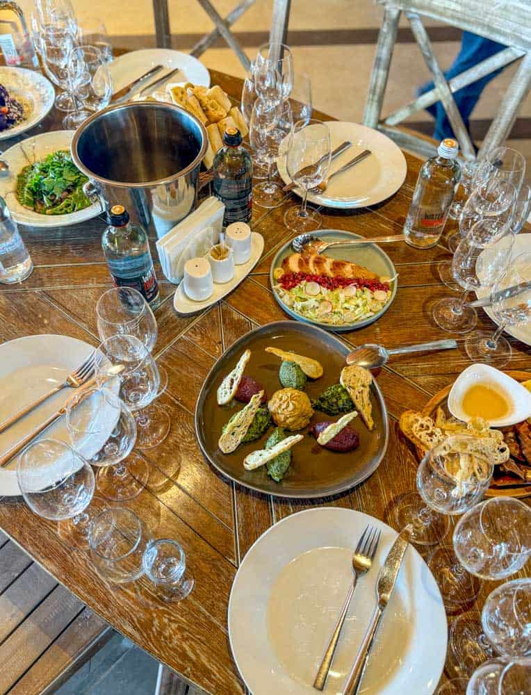 A table full of food and wine on a wooden table.