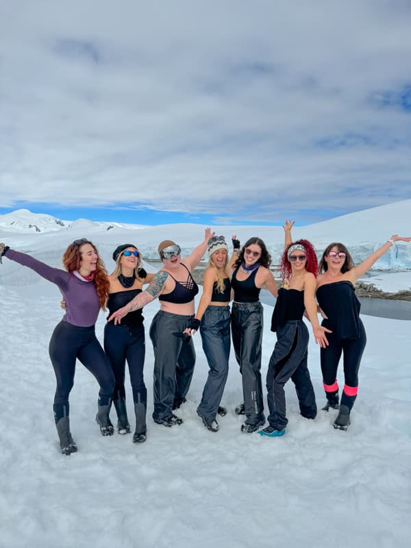 six women wearing black pose on top of a glacier in antarctica