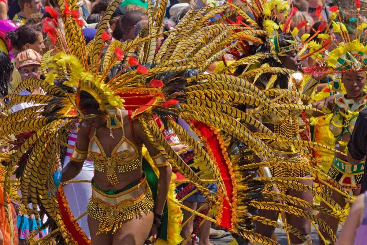 Participants in vibrant, feathered costumes at a carnival parade, with focus on elaborate headpieces and colorful attire.